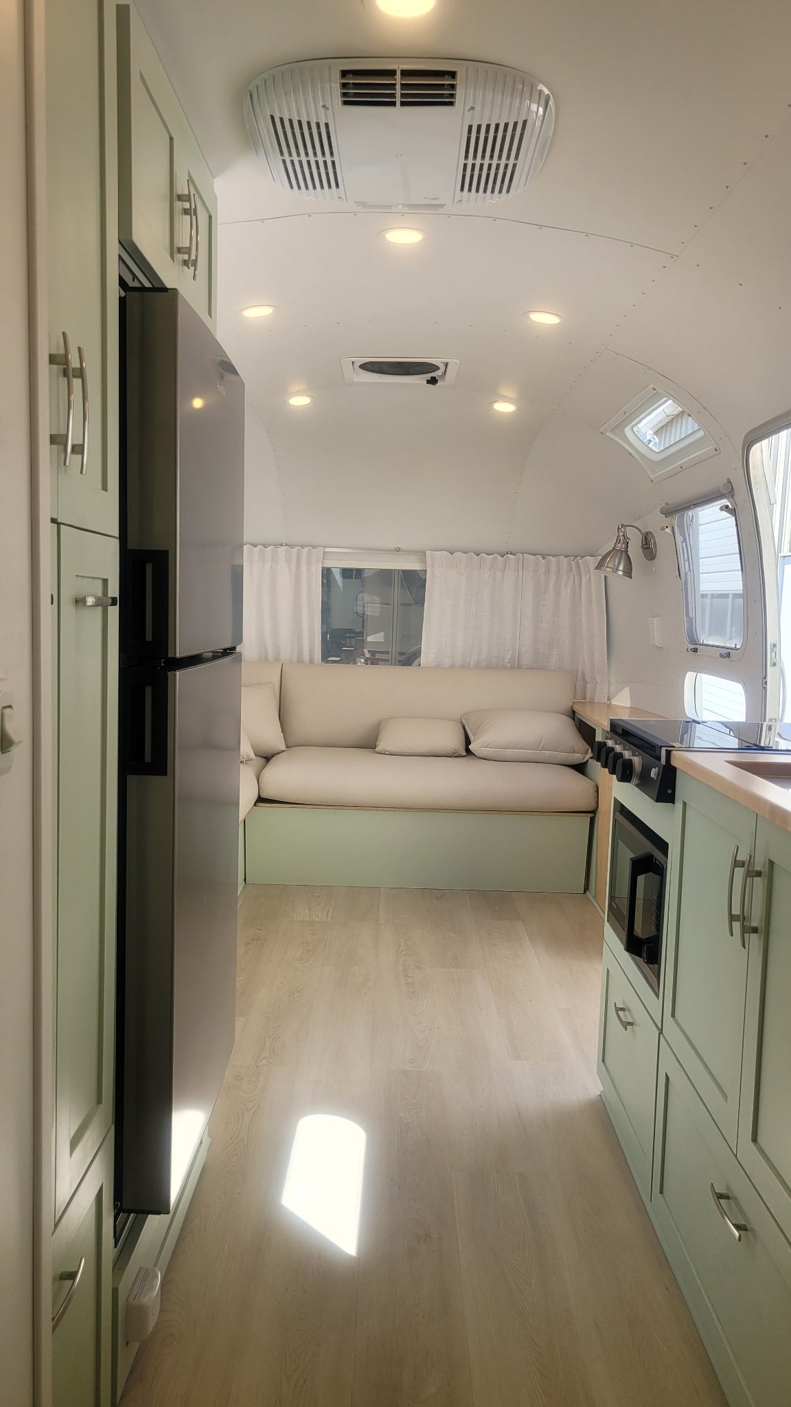 Completed custom Airstream renovation with sage cabinetry, full galley, lounge seating and integrated systems by NuAbode